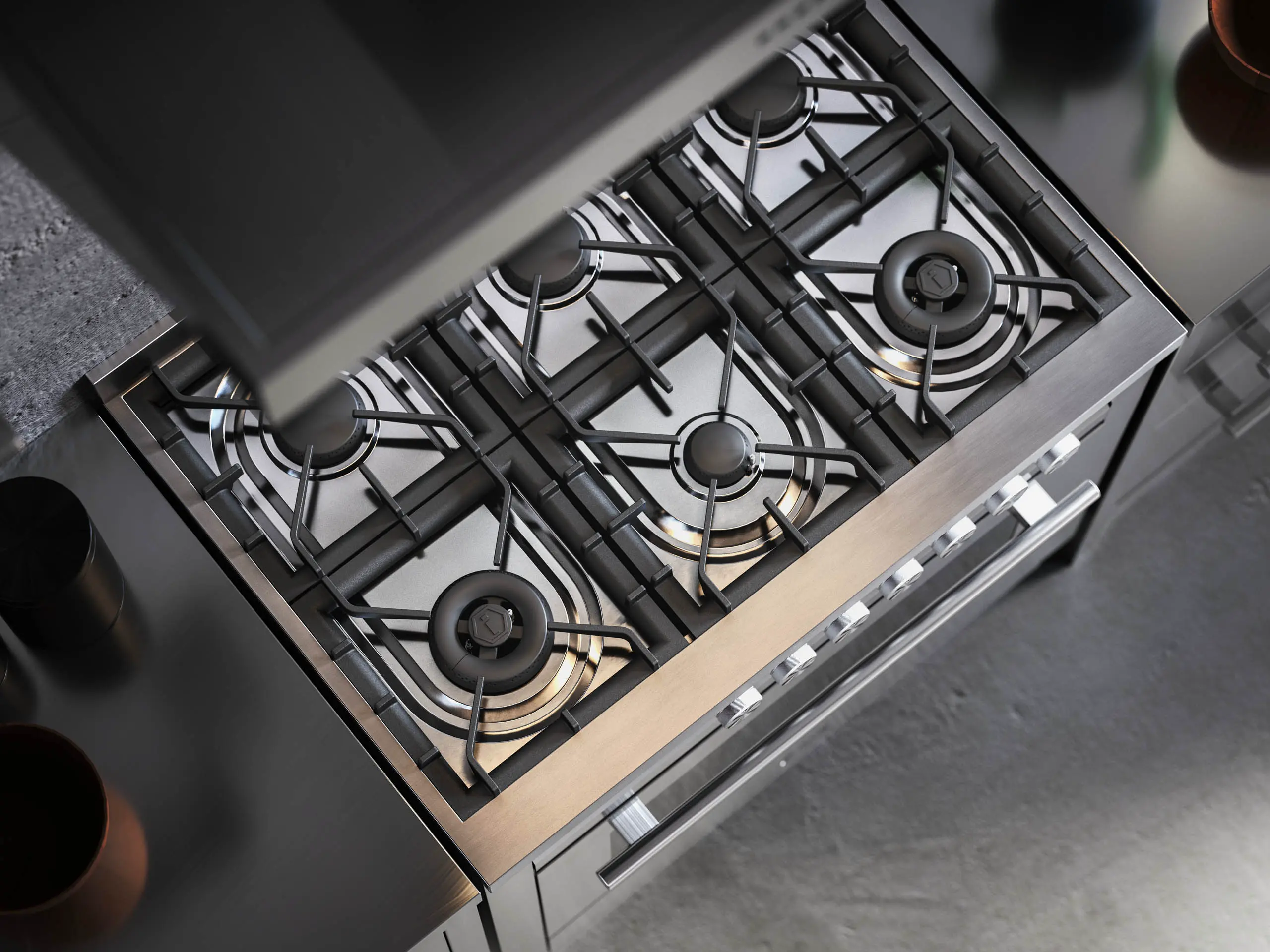 Top-downvy av en modern spishäll i rostfritt stål med fyra brännare, placerad på en ren köksbänk.